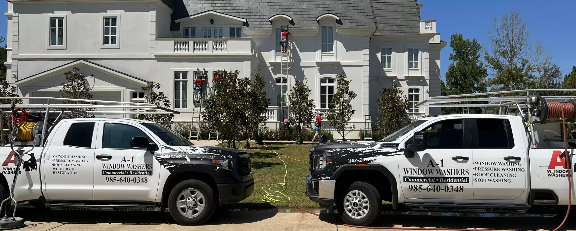 Two A-1 Window washer trucks in front of a house cleaning