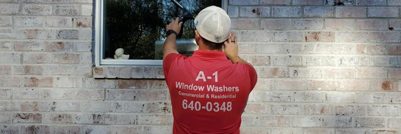 Image of house washing professional washing a window on a brick house