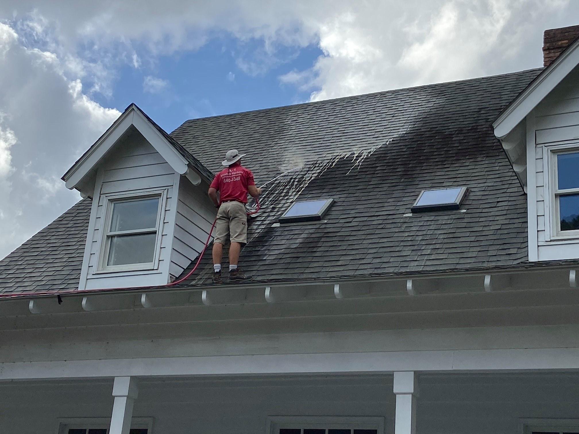 image of a house washing professional washing a roof on a house in Covington